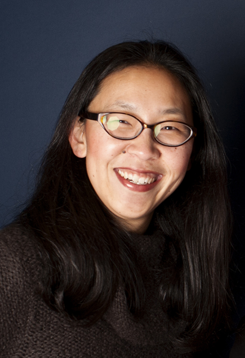 An Asian woman with black hair and brown glasses smiles 
