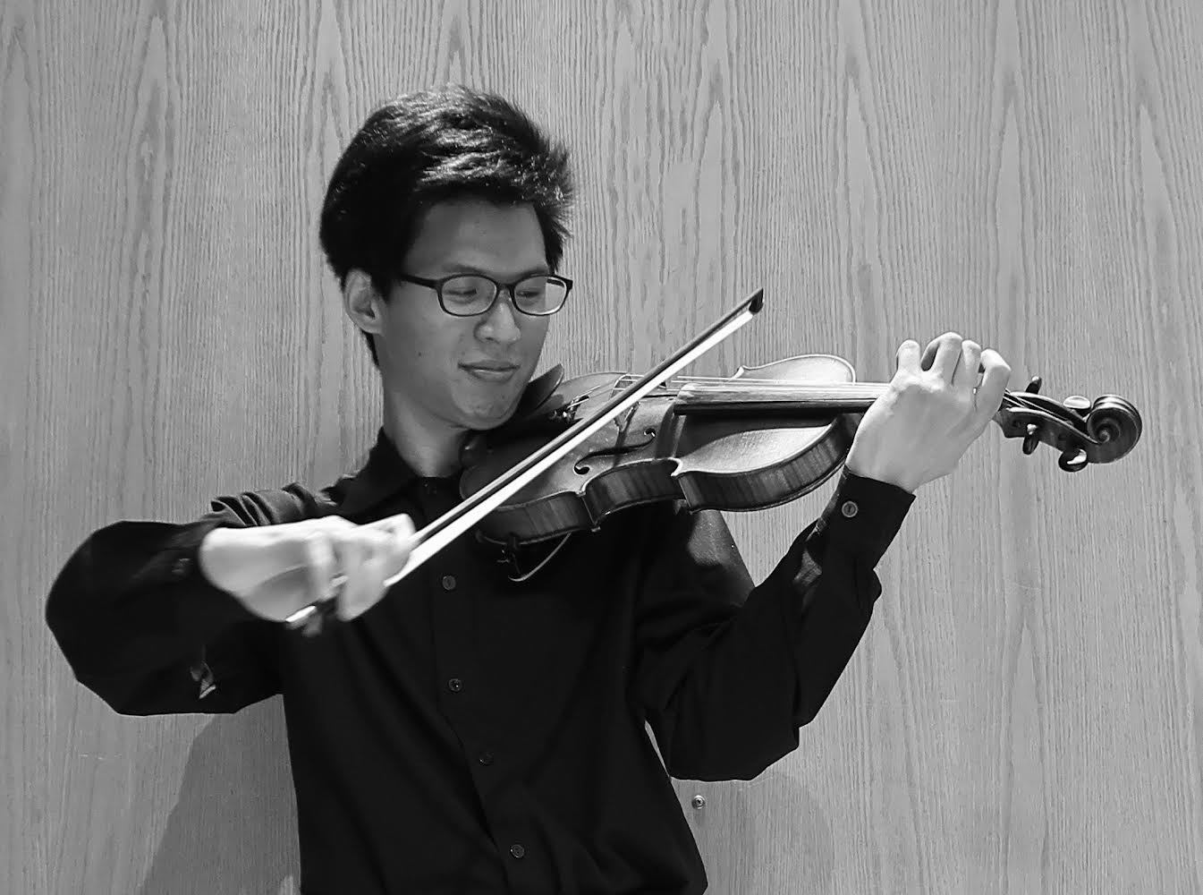 A black and white photo of a young Asian man holding a violin